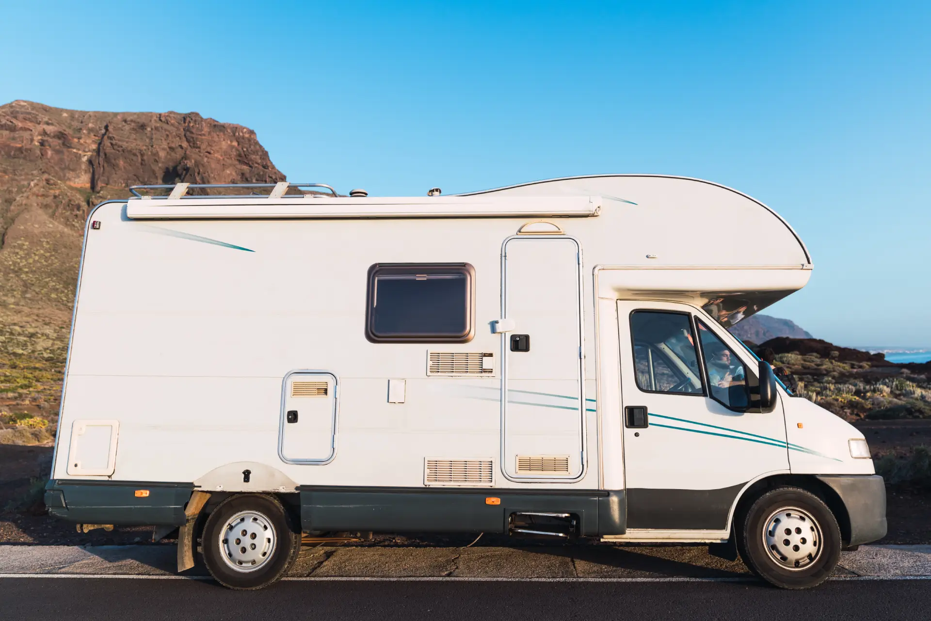camper-van-on-road-near-hill-and-blue-sky-2025-04-04-22-02-13-utc